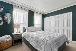 Carpeted bedroom featuring a closet and crown molding