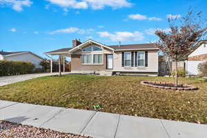 Single story home featuring a front yard and a carport