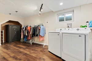 Washroom with dark hardwood / wood-style floors, independent washer and dryer, electric panel, and track lighting