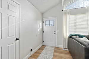 Foyer featuring light hardwood / wood-style floors, lofted ceiling, and a textured ceiling