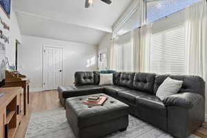 Living room featuring lofted ceiling with beams, light hardwood / wood-style floors, and ceiling fan