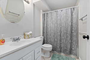 Bathroom featuring curtained shower, tile patterned flooring, vanity, and toilet