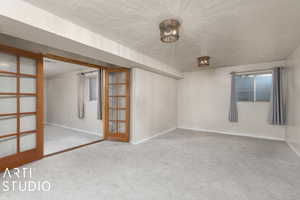 Carpeted spare room featuring french doors and a textured ceiling