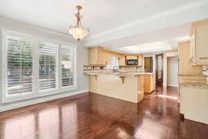 Dining area with hanging light fixtures, a breakfast bar, plenty of natural light, and dark wood-type flooring