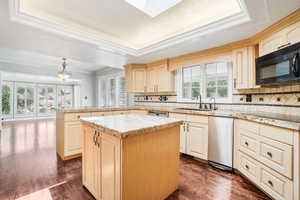 Kitchen with sink, a kitchen island, a wealth of natural light, and coved ceiling with skylight