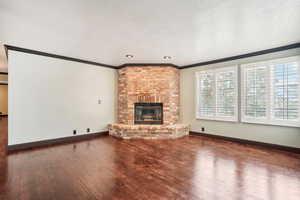 Unfurnished living room with crown molding, a textured ceiling, and a brick fireplace