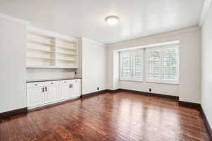 Formal Dining  or Living Room, or in-home office featuring a textured ceiling, built in shelves and cabinetry, plantation shutters, and handscraped hardwood flooring