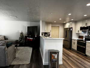 Kitchen featuring white cabinetry, dark hardwood / wood-style flooring, a textured ceiling, and appliances with stainless steel finishes