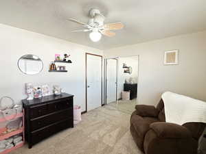 Living area featuring carpet, a textured ceiling, and ceiling fan