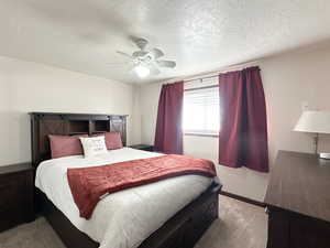 Carpeted bedroom with ceiling fan and a textured ceiling