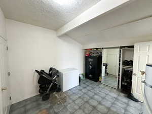 Basement featuring water heater, a textured ceiling, and fridge