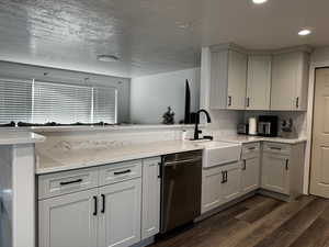 Kitchen featuring white cabinets, sink, stainless steel dishwasher, a textured ceiling, and dark hardwood / wood-style flooring