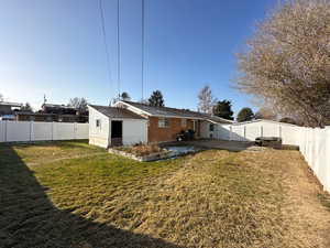 Rear view of property with a lawn and a patio area