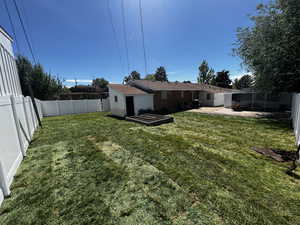 Rear view of house featuring a patio, a storage shed, and a lawn