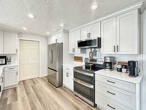 Kitchen featuring appliances with stainless steel finishes, a textured ceiling, and white cabinetry