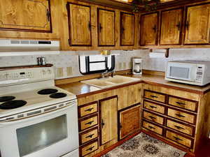 Kitchen with white appliances, extractor fan, and sink