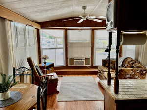 Sunroom / solarium with cooling unit, a wealth of natural light, lofted ceiling, and ceiling fan