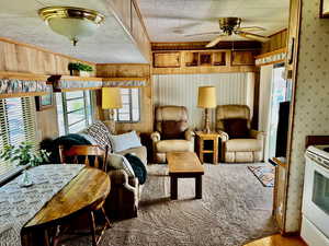 Living room featuring hardwood / wood-style flooring, ceiling fan, ornamental molding, and wood walls