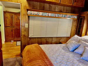 Bedroom with hardwood / wood-style flooring and wooden walls