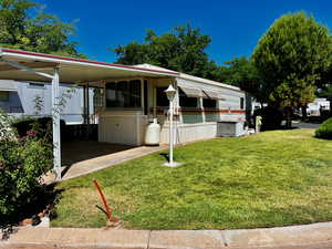 View of side of property with a yard, central AC unit, and a carport