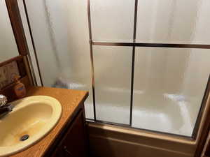 Bathroom featuring combined bath / shower with glass door and sink