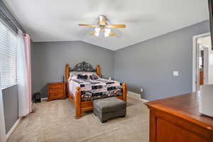 Carpeted bedroom with ceiling fan and lofted ceiling