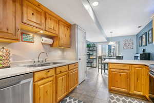 Kitchen featuring hanging light fixtures, tile patterned flooring, stainless steel appliances, and sink