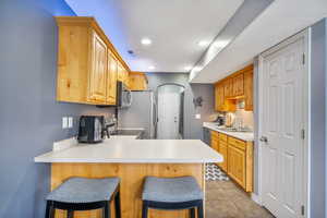 Kitchen featuring sink, stainless steel appliances, kitchen peninsula, a kitchen bar, and light tile patterned flooring