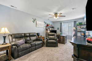 Carpeted living room with a textured ceiling and ceiling fan