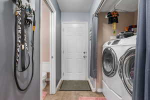 Laundry room featuring washer and dryer, light tile patterned floors, and a textured ceiling