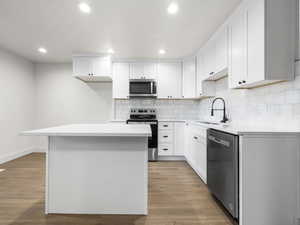 Kitchen with white cabinets, sink, a center island, and stainless steel appliances