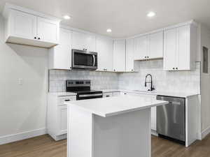 Kitchen with dark hardwood / wood-style floors, white cabinetry, and stainless steel appliances