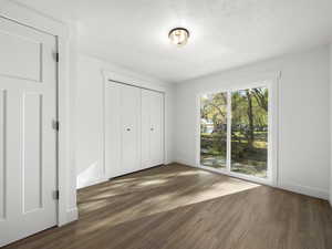 Unfurnished bedroom with a closet, dark hardwood / wood-style flooring, and a textured ceiling