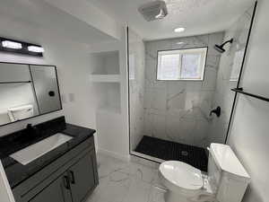 Bathroom with a tile shower, vanity, and toilet