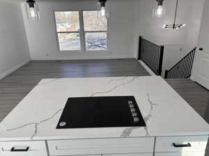 Interior space with light stone countertops, a chandelier, pendant lighting, and dark hardwood / wood-style floors