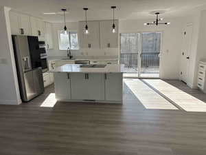 Kitchen with stainless steel fridge with ice dispenser, a center island, white cabinets, and dark hardwood / wood-style floors