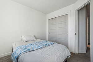 Bedroom with dark colored carpet and a closet