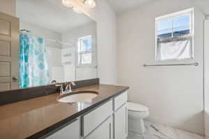 Bathroom featuring toilet, vanity, and plenty of natural light