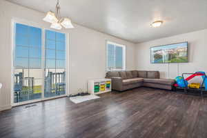 Living room with dark wood-type flooring and an inviting chandelier