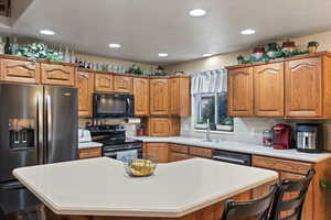 Kitchen with black appliances, a kitchen breakfast bar, a kitchen island, and sink