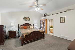 Carpeted bedroom featuring ensuite bath, ceiling fan, and vaulted ceiling