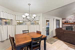 Tiled dining room featuring a fireplace, a chandelier, and lofted ceiling