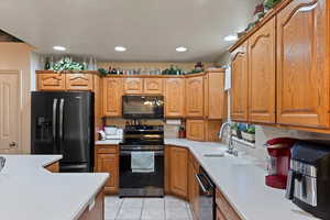 Kitchen featuring black appliances, light tile patterned floors, and sink