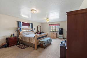 Carpeted bedroom featuring ceiling fan and a textured ceiling