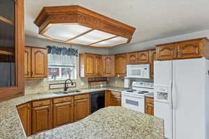 Kitchen featuring sink, tasteful backsplash, light stone counters, a textured ceiling, and white appliances