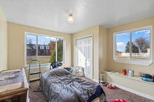 Carpeted bedroom featuring a textured ceiling and a closet