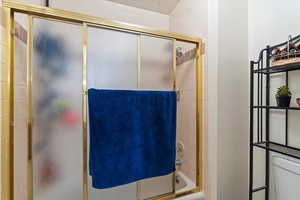 Bathroom featuring combined bath / shower with glass door and toilet