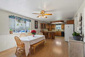 Dining area featuring a textured ceiling, light wood-type flooring, ceiling fan, and sink