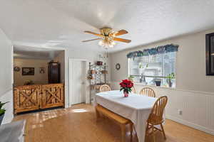 Dining space with a textured ceiling, light hardwood / wood-style floors, and ceiling fan