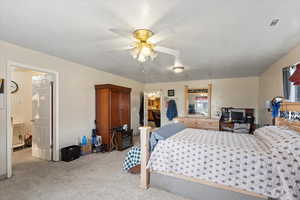 Carpeted bedroom with ceiling fan, a textured ceiling, and ensuite bath